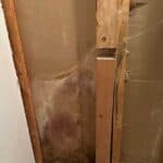 Close-up view of exposed wooden wall studs and drywall